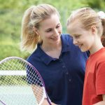 Camp Counselor coaching camper with Tennis