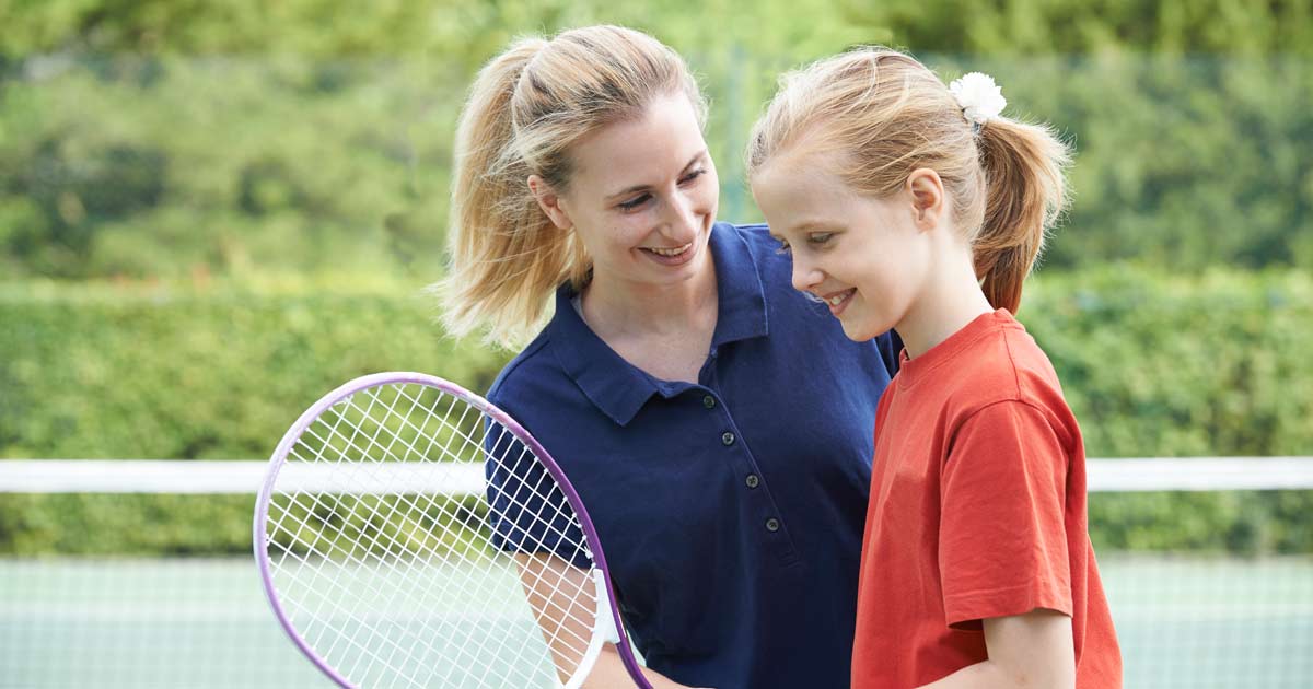 Camp Counselor coaching camper with Tennis