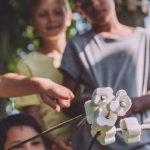 Group of children roasting marshmallows on sticks together at a summer camp campfire