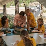 Counselor with campers doing arts and crafts